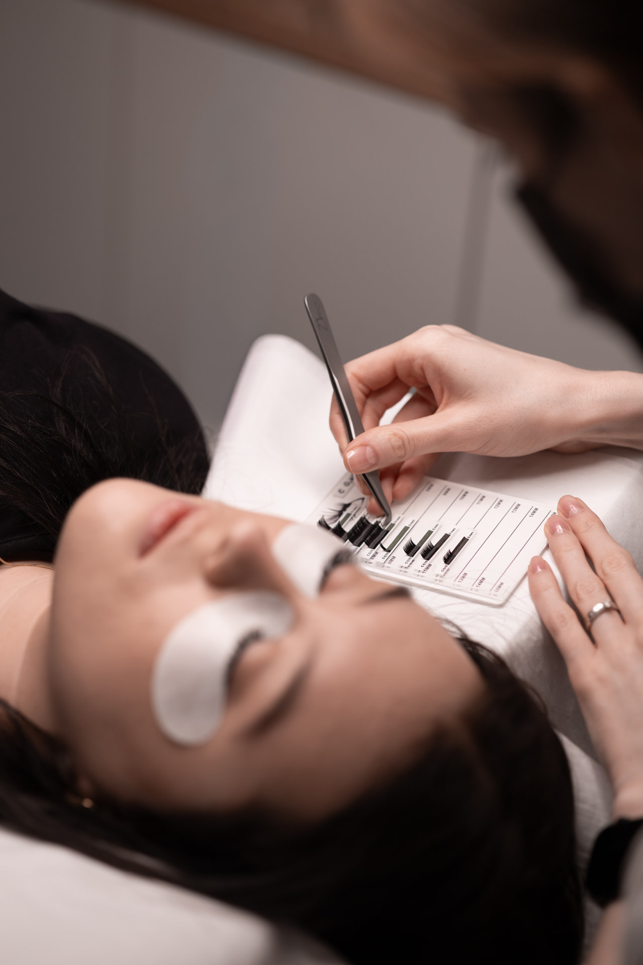 Przedłużanie rzęs w Białymstoku — stylistka SKiN aplikuje rzęsy pęsetą, dobór długości z palety